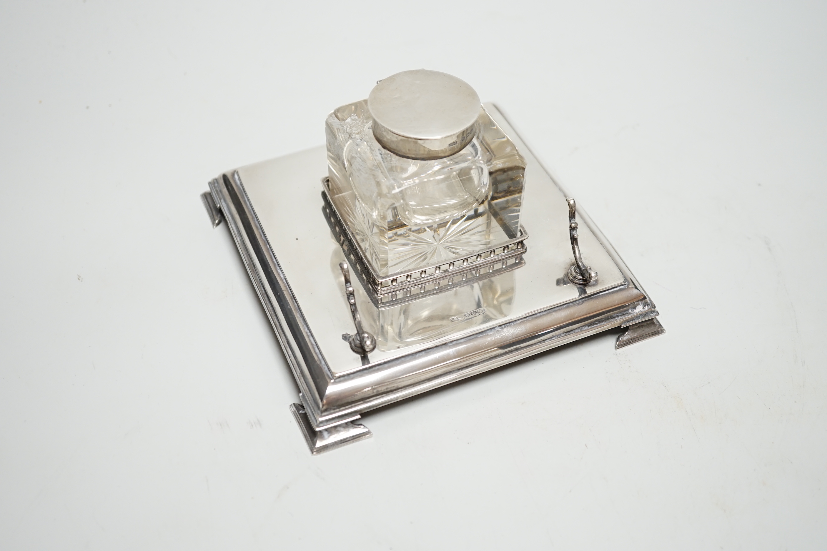 A George V silver inkwell, with mounted glass well and pen rest, James Dixon & Sons, Sheffield, 1928, 15.2cm, base 7.3oz.